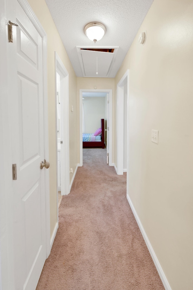 corridor featuring light colored carpet and a textured ceiling