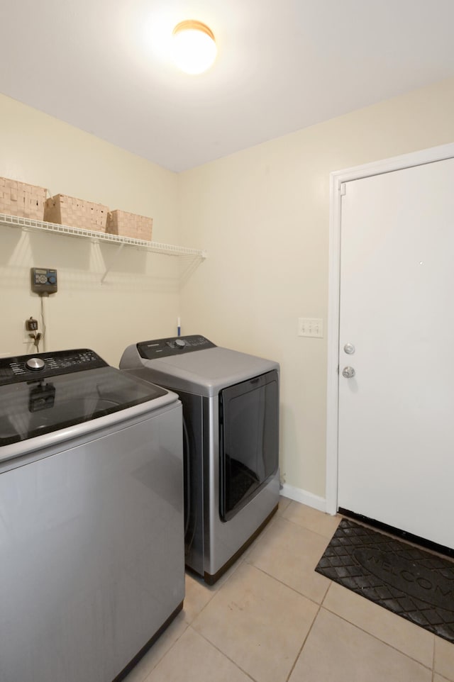 clothes washing area featuring light tile patterned flooring and independent washer and dryer