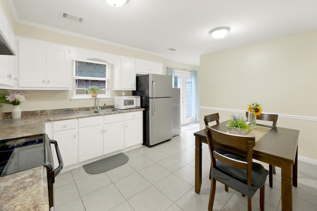 kitchen with white cabinetry, sink, and stainless steel refrigerator