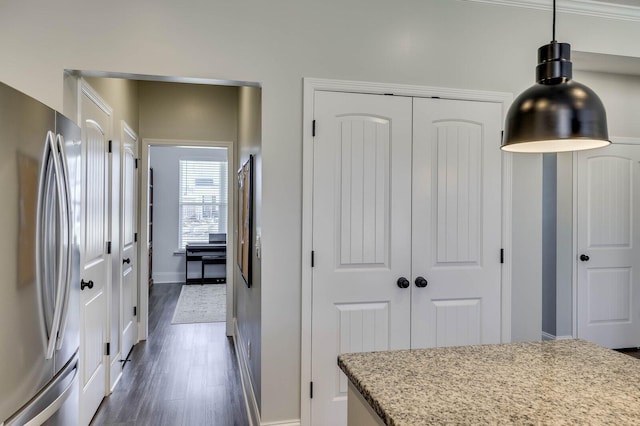 kitchen with light stone counters, baseboards, dark wood-style flooring, freestanding refrigerator, and hanging light fixtures