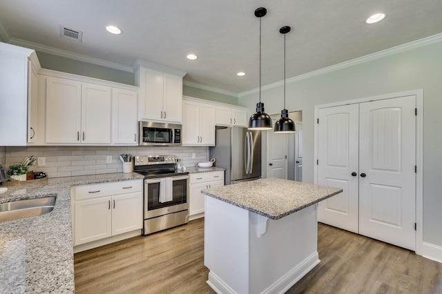 kitchen with visible vents, stainless steel appliances, wood finished floors, and a sink