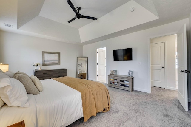 bedroom featuring visible vents, light colored carpet, a raised ceiling, and baseboards