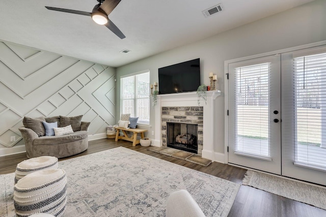 living room featuring a fireplace, wood finished floors, visible vents, and baseboards