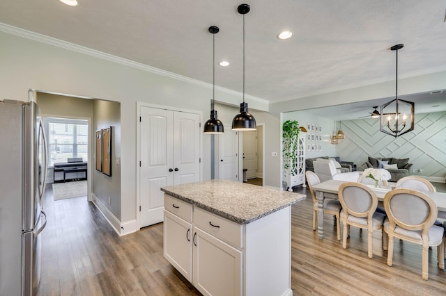 kitchen featuring wood finished floors, ornamental molding, and freestanding refrigerator