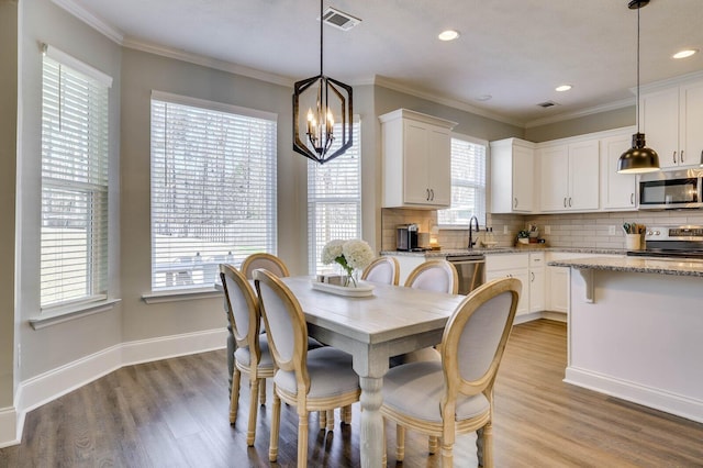 dining room with visible vents, light wood-style floors, and ornamental molding