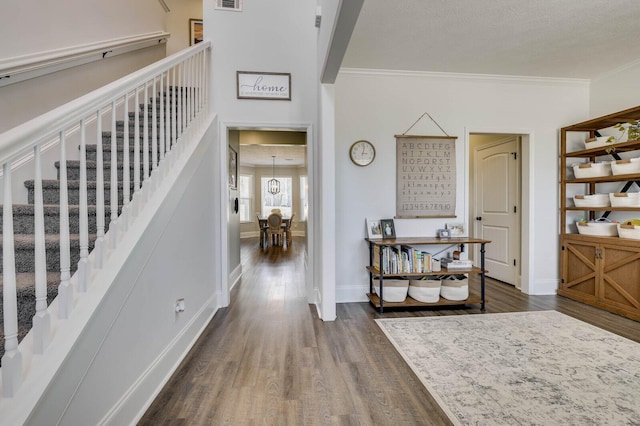 foyer featuring stairway, baseboards, visible vents, dark wood-type flooring, and crown molding