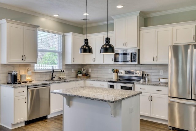 kitchen featuring a sink, dark wood-type flooring, appliances with stainless steel finishes, crown molding, and a center island