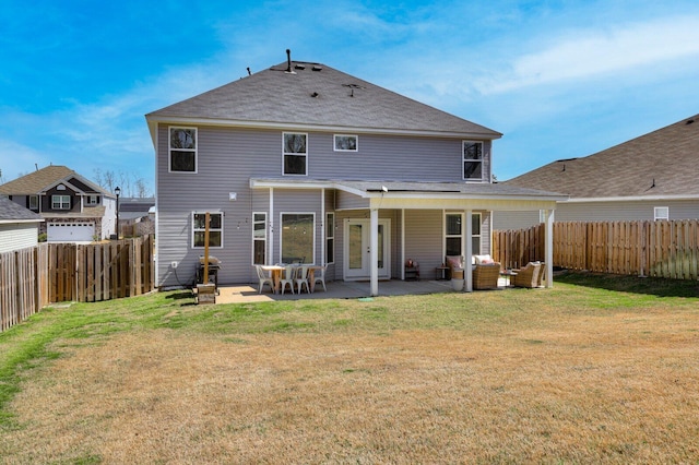 rear view of house with a patio, a lawn, and a fenced backyard