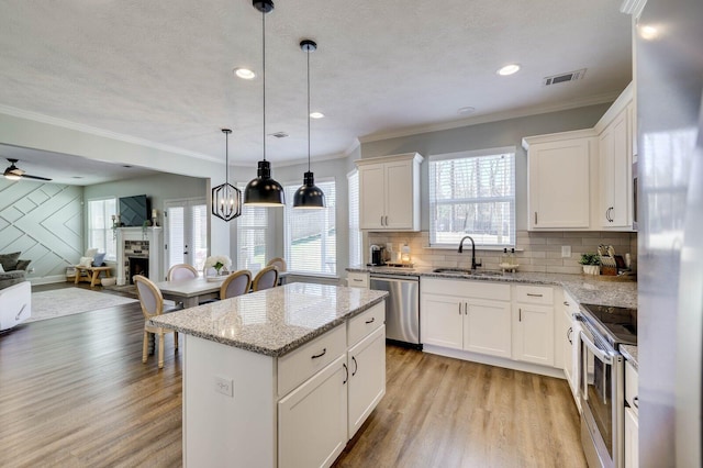 kitchen with visible vents, a fireplace, a sink, stainless steel appliances, and light wood-style floors