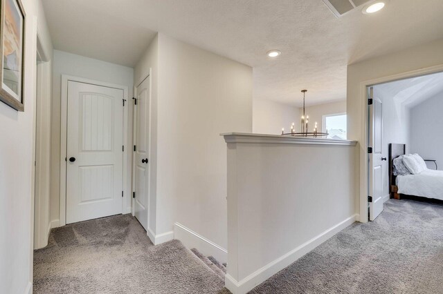 hallway with visible vents, a notable chandelier, recessed lighting, carpet floors, and baseboards