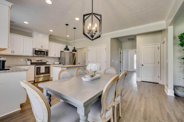 dining space featuring wood finished floors, recessed lighting, an inviting chandelier, crown molding, and baseboards