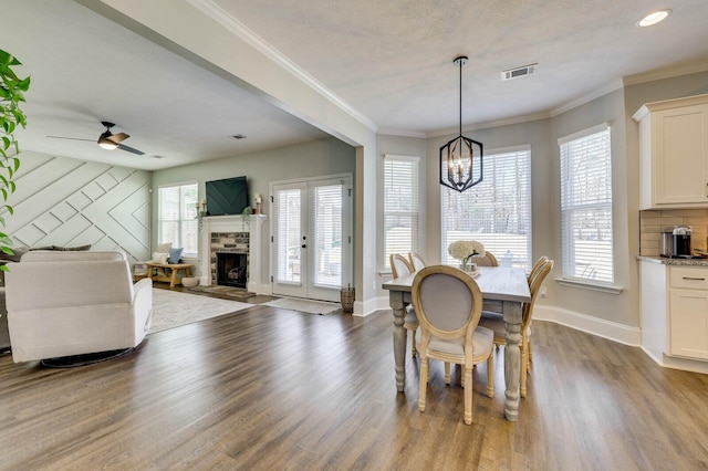 dining room featuring baseboards, visible vents, a fireplace with raised hearth, dark wood-type flooring, and crown molding