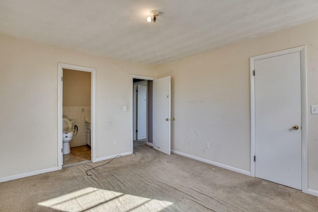 unfurnished bedroom with light carpet and ensuite bath