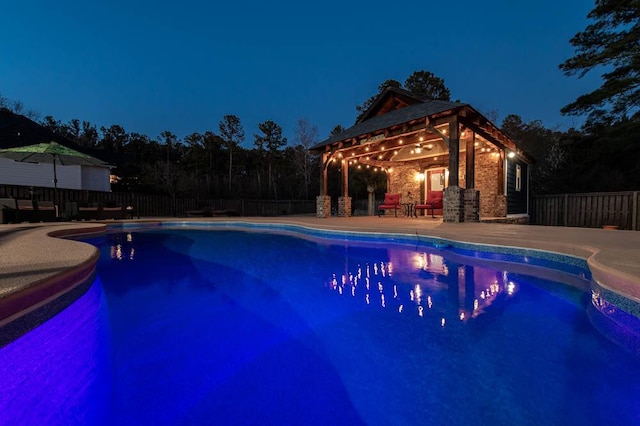 pool at night featuring a fenced in pool, a patio area, a fenced backyard, and a gazebo