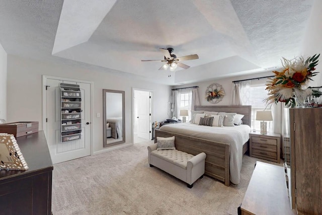 bedroom featuring a raised ceiling, a textured ceiling, and light colored carpet
