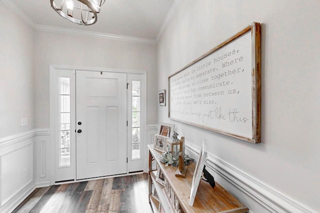 entryway featuring crown molding, an inviting chandelier, wainscoting, and wood finished floors