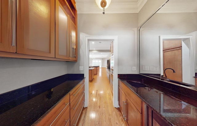 kitchen with sink, light hardwood / wood-style floors, and dark stone counters