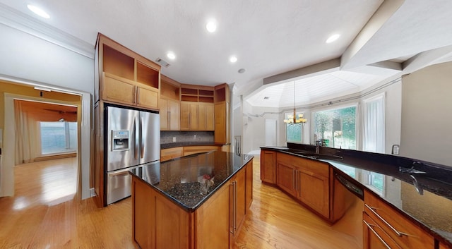 kitchen with sink, a kitchen island, pendant lighting, stainless steel appliances, and light hardwood / wood-style floors