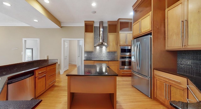 kitchen featuring tasteful backsplash, appliances with stainless steel finishes, a center island, and wall chimney range hood