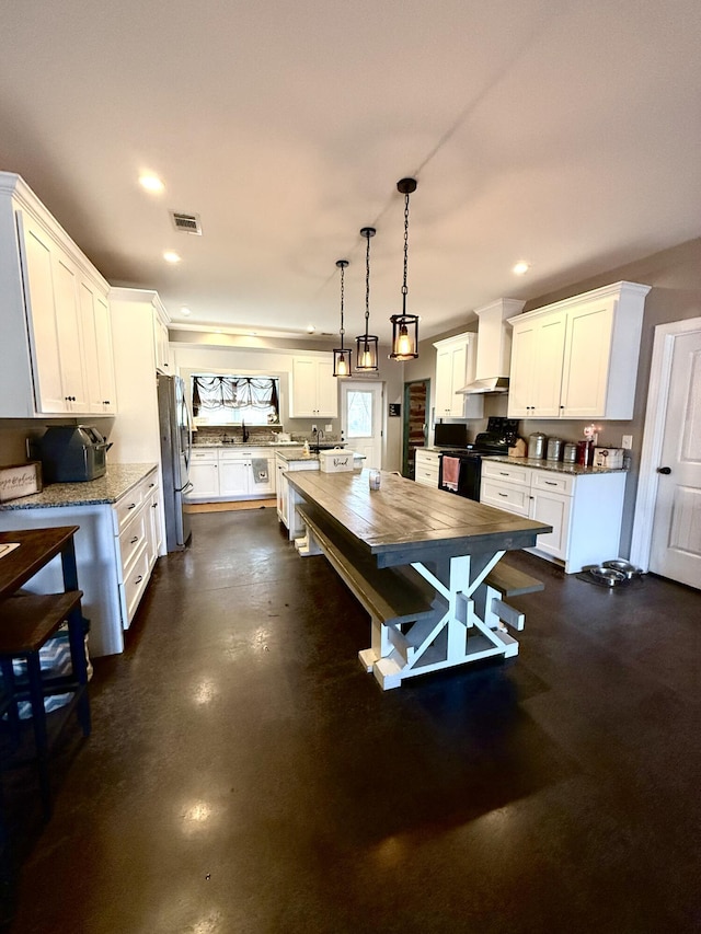 kitchen with pendant lighting, stainless steel refrigerator, white cabinets, electric range, and wall chimney range hood