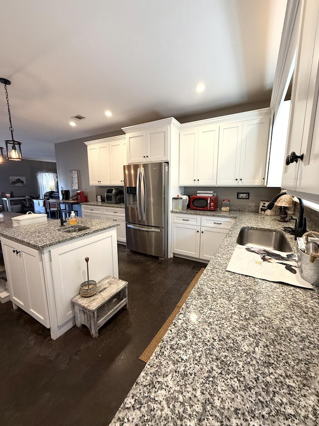 kitchen featuring stainless steel refrigerator with ice dispenser, light stone countertops, sink, and white cabinets