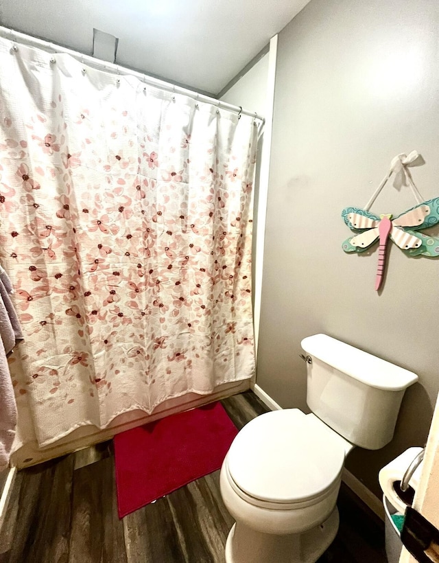 bathroom featuring shower / tub combo with curtain, hardwood / wood-style flooring, and toilet