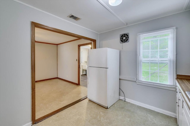 kitchen featuring white refrigerator and white cabinetry