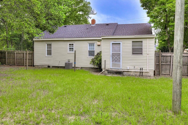 back of property featuring cooling unit and a lawn