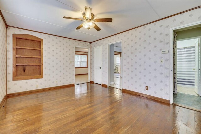 empty room with ceiling fan, wood-type flooring, and ornamental molding