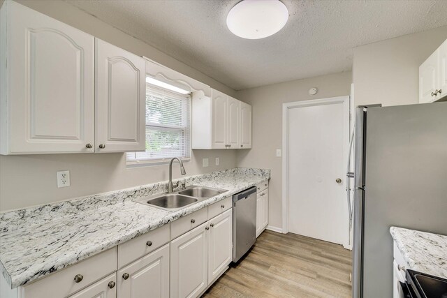 2913 Kings View Dr, Augusta, GA 30909 - kitchen with stainless steel appliances, light wood finished floors, white cabinets, and a textured ceiling
