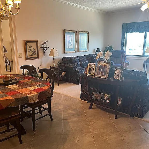 tiled dining space featuring crown molding, a textured ceiling, and a notable chandelier