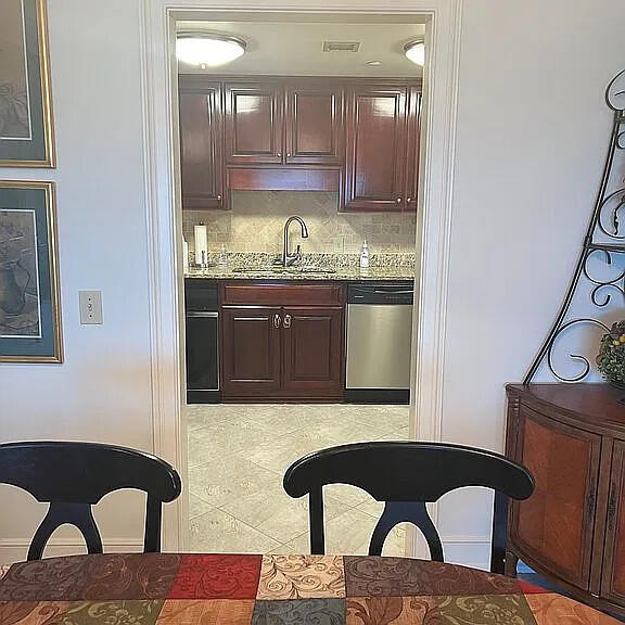 kitchen with light stone countertops, dishwasher, sink, decorative backsplash, and dark brown cabinets