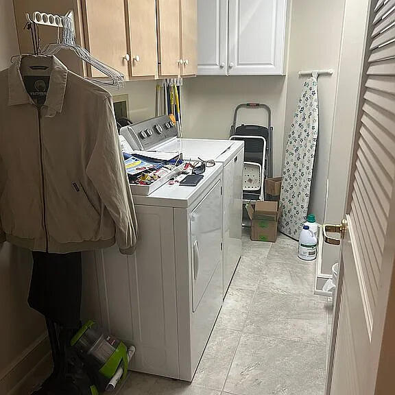 laundry room with washer and clothes dryer, cabinets, and light tile patterned floors