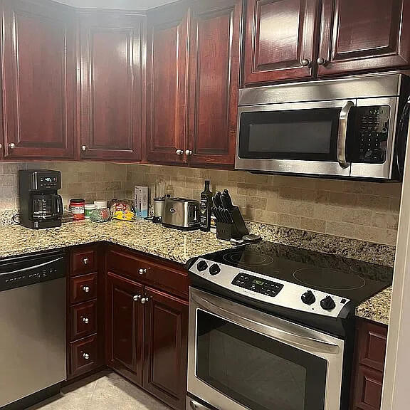 kitchen featuring tasteful backsplash, light stone countertops, and stainless steel appliances