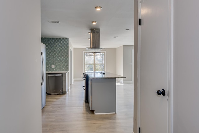 kitchen featuring decorative backsplash, light wood-type flooring, a kitchen island, stainless steel appliances, and extractor fan