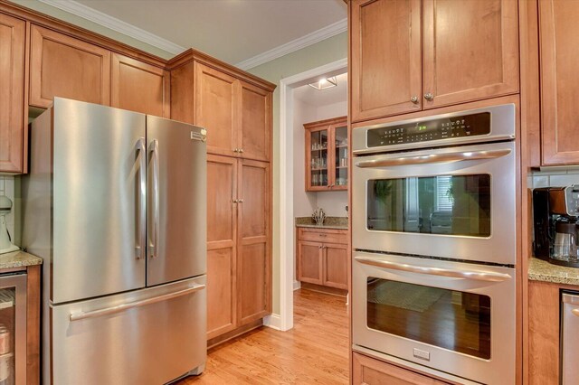 4002 Backwater Ct, Evans, GA 30809 - kitchen with light stone countertops, light wood-type flooring, ornamental molding, stainless steel appliances, and brown cabinets