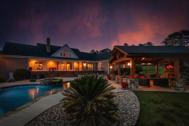 698 Heggies Ridge Dr, Appling, GA 30802 - back of property at dusk with a chimney, a patio, an outdoor bar, a yard, and a pool with connected hot tub