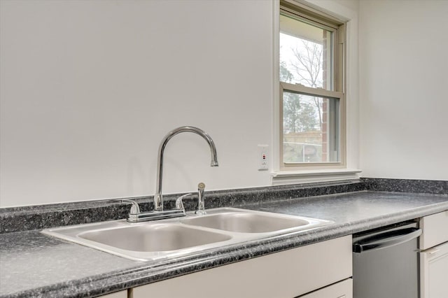 kitchen with dishwasher, white cabinetry, and sink