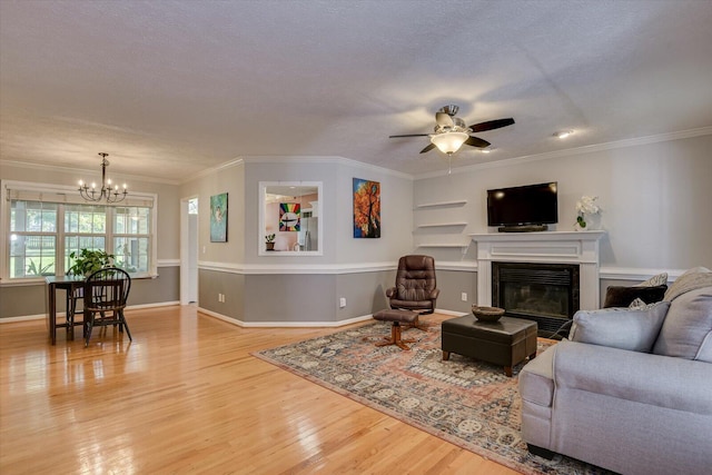 living room featuring a textured ceiling, ceiling fan with notable chandelier, light hardwood / wood-style flooring, and crown molding