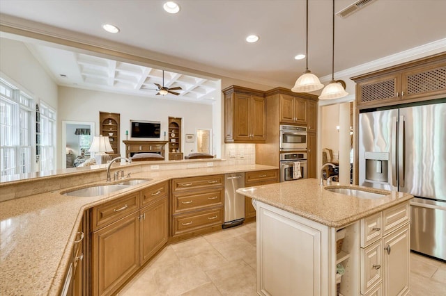 kitchen featuring appliances with stainless steel finishes, an island with sink, sink, coffered ceiling, and light stone countertops