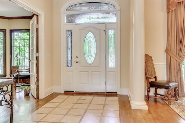 foyer entrance featuring ornamental molding, light hardwood / wood-style flooring, and decorative columns