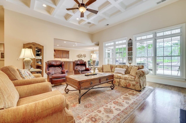 living room with beamed ceiling, a towering ceiling, a healthy amount of sunlight, and light wood-type flooring