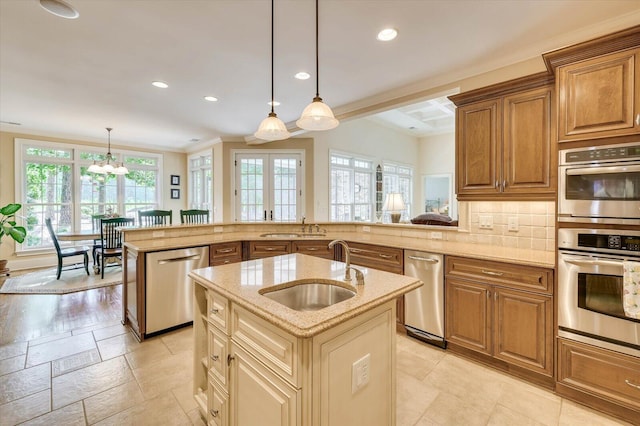 kitchen featuring sink, appliances with stainless steel finishes, an island with sink, decorative backsplash, and decorative light fixtures