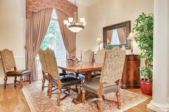 dining room featuring crown molding, a chandelier, light hardwood / wood-style flooring, and ornate columns