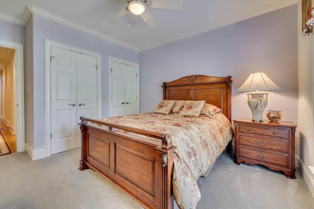 bedroom featuring multiple closets, crown molding, light colored carpet, and ceiling fan