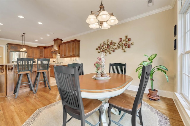 dining space with crown molding, a chandelier, and light hardwood / wood-style flooring