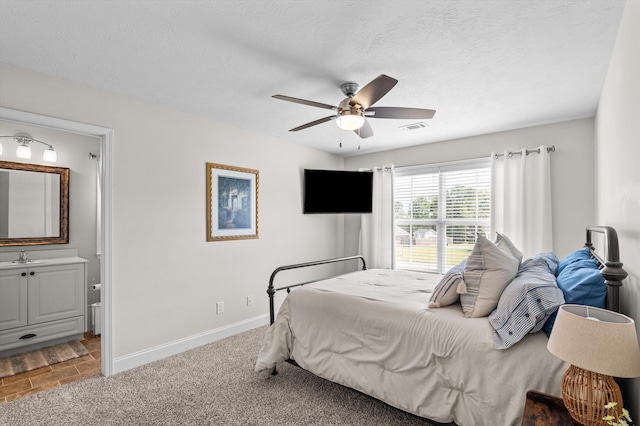 bedroom featuring baseboards, ensuite bath, and a ceiling fan