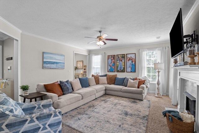 living room featuring a fireplace with flush hearth, ceiling fan, crown molding, a textured ceiling, and carpet
