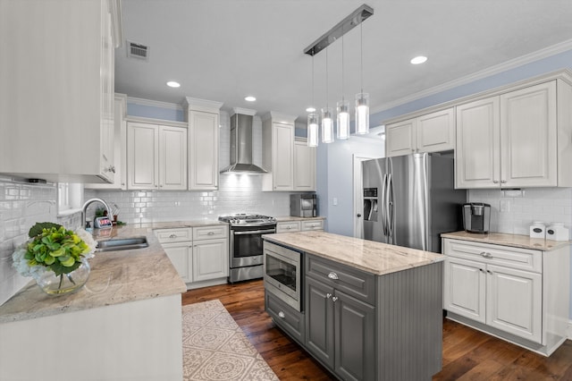 kitchen featuring wall chimney range hood, appliances with stainless steel finishes, a sink, gray cabinets, and backsplash