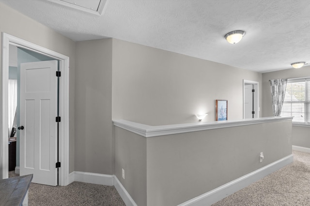 corridor with carpet flooring, baseboards, and a textured ceiling